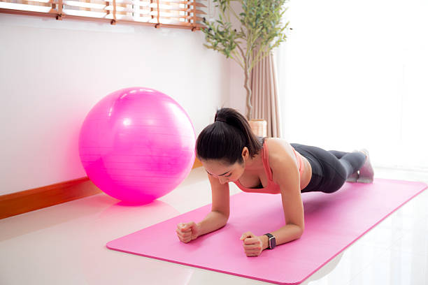 istock Young asian woman practice workout with posing plank on mat while motivation and determined at home, female doing weight training with strength and strong, one person, lifestyles and sport concept. 2203061569