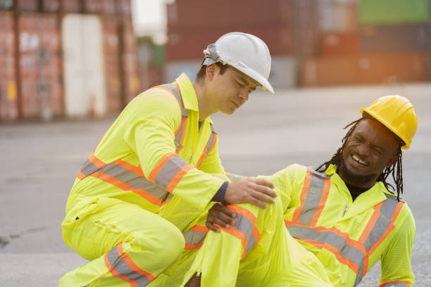 istock Workers accident, helping injured worker, Accident concept. Male worker had accident at container cargo site control loading containers boxes. Health safe of work and safety first concept 2203062873