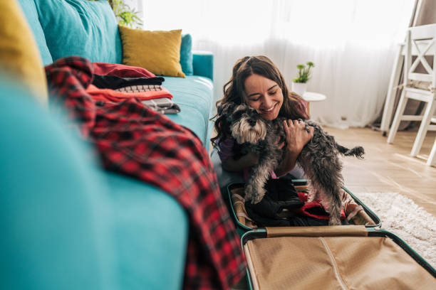 istock Woman packing suitcase with clothes and hugging dog before trip 2203063329