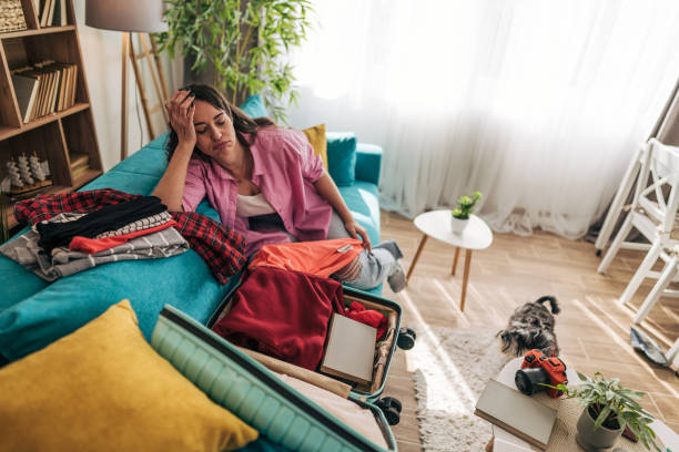 istock Stressed woman packing clothes into suitcase at home 2203063760