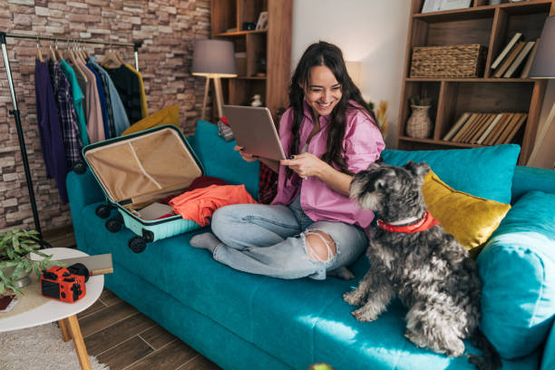 istock Young woman planning a trip with her dog and using a laptop 2203063998