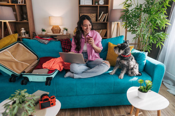 istock Young woman planning a trip with her dog on the sofa 2203064111