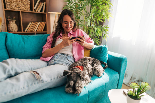 istock Woman relaxing on sofa with dog and using smartphone at home 2203064445