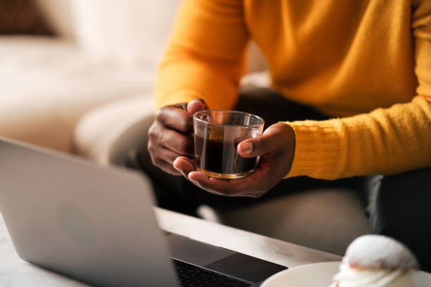 Man enjoying coffee and pastry while working on laptop at home