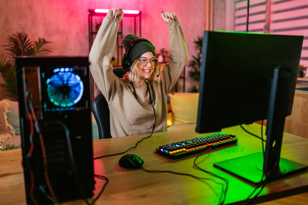 Beautiful young woman winning while playing a video game on her desktop pc at home.