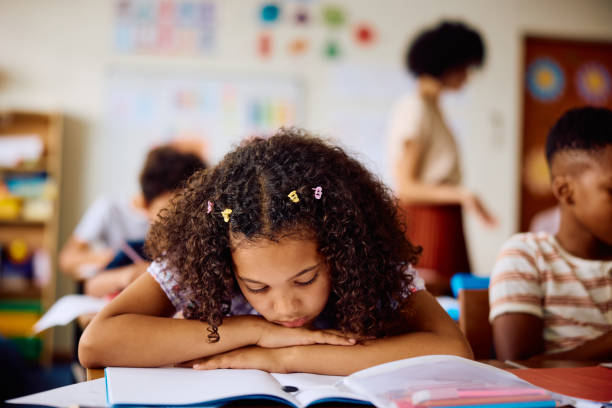 istock Schoolgirl leaning on desk in class, daydreaming 2203067419