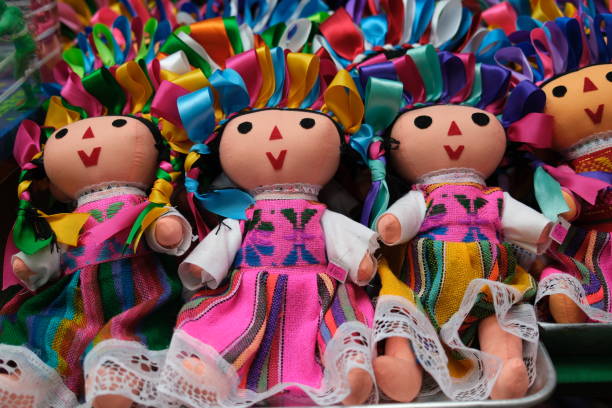 Close-up of traditional handmade Mexican dolls, each dressed in pink embroidered dresses and decorated with bright satin ribbon headpieces.
