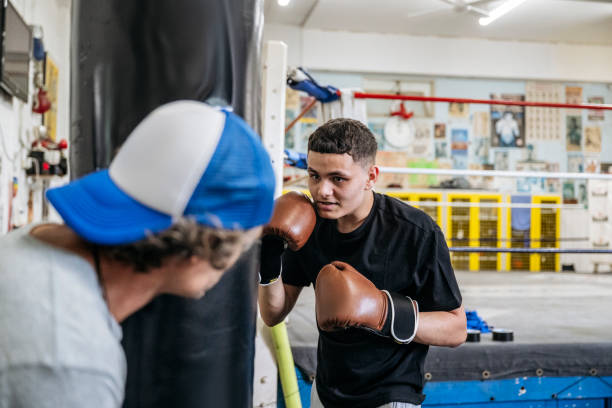 istock Coach supporting 16-year-old boxer training on heavy bag 2203068003