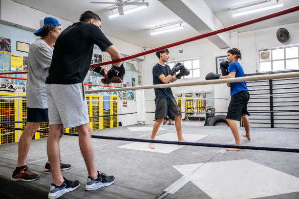 istock Mature trainer and young boxer watching sparring partners 2203068119