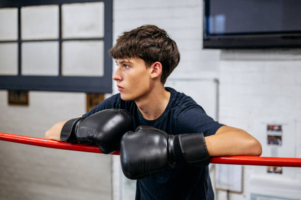 istock Young male fighter watching closely from side of boxing ring 2203068172