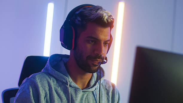 istock Pro male gamer playing video game on desktop computer, live streaming sits in a Neon led light gaming room 2203068424