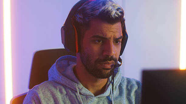 istock Pro male gamer playing video game on desktop computer, live streaming sits in a Neon led light gaming room 2203068443