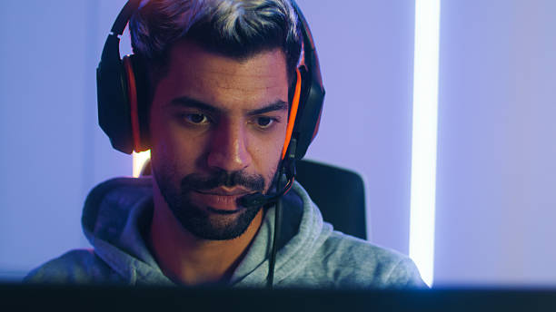 istock Pro male gamer playing video game on desktop computer, live streaming sits in a Neon led light gaming room 2203068485