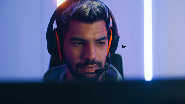 istock Pro male gamer playing video game on desktop computer, live streaming sits in a Neon led light gaming room 2203068544