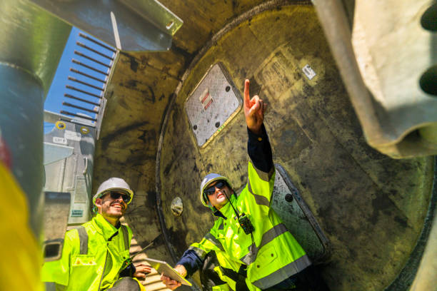 istock Two engineers in safety gear inspecting a wind turbine blade section on a construction site. They examine the metal framework with precision. Renewable energy project under a clear blue sky. 2203068568