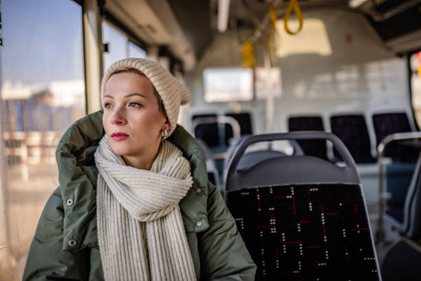 istock Young woman enjoys a bus ride through the city with a cheerful expression while looking out the window on a sunny day 2203070102