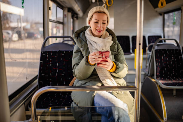 istock Young woman enjoys her commute on a city bus while smiling and using her smartphone 2203071398