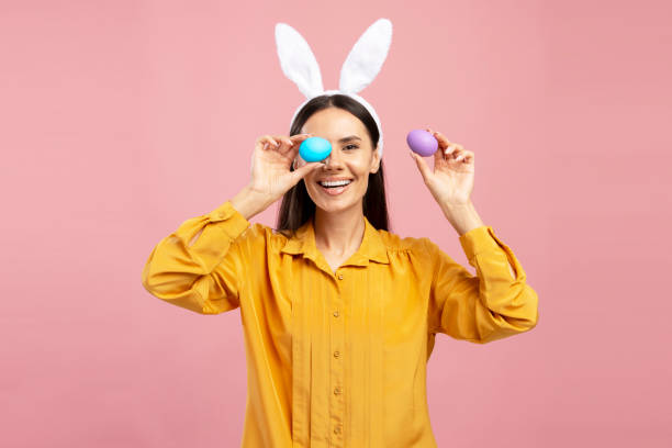 istock Woman wearing bunny ears holding easter eggs and smiling 2203071558