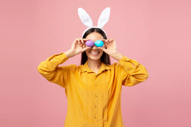 istock Young woman holding easter eggs in front of her eyes and smiling 2203071629