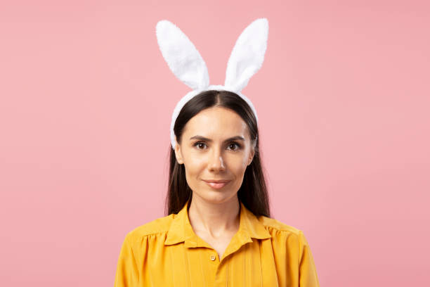 istock Young woman wearing bunny ears headband looking at camera 2203072043
