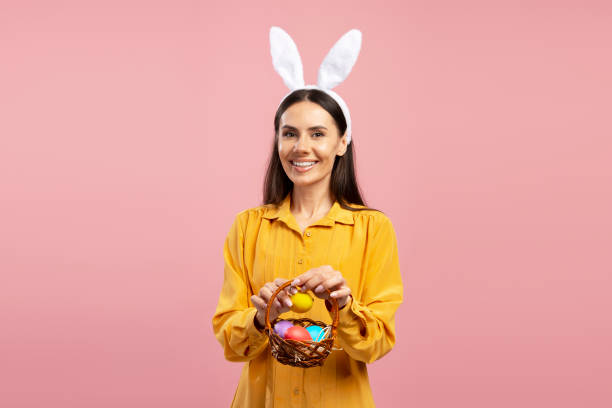 istock Woman wearing bunny ears holding easter eggs basket smiling at camera 2203072047