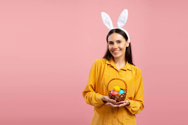 istock Young woman holding easter eggs basket wearing bunny ears headband 2203072240