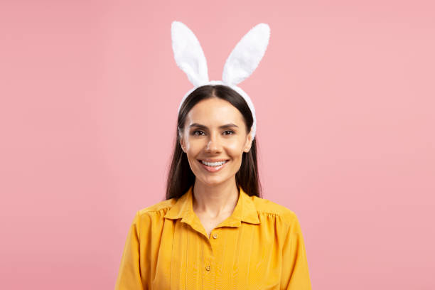 Smiling woman wearing bunny ears headband for Easter celebration