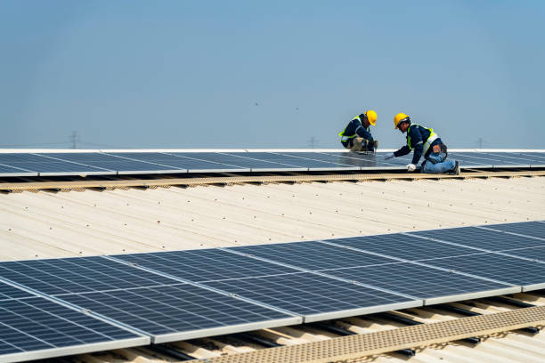 istock Two engineers install solar panels on a rooftop, wearing safety gear and helmets. The scene showcases renewable energy, green technology, and sustainable solutions under a clear blue sky. 2203072851