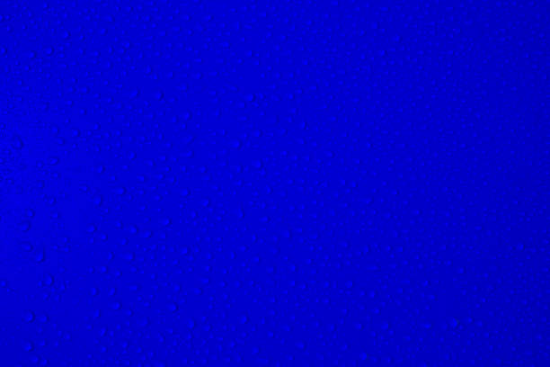 Drops on blue background. Water drops on dark blue tone background. Blue colour Abstarct wet texture with bubbles. Raindrop close up, pure water droplets for bright banner design. Transparent glass.