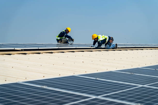 istock Two engineers install solar panels on a rooftop, wearing safety gear and helmets. The scene showcases renewable energy, green technology, and sustainable solutions under a clear blue sky. 2203074380