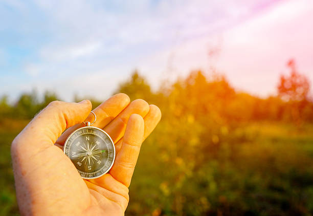 istock Compass in hand on blue sky background. Tourist compass for orientation on terrain. 2203074851