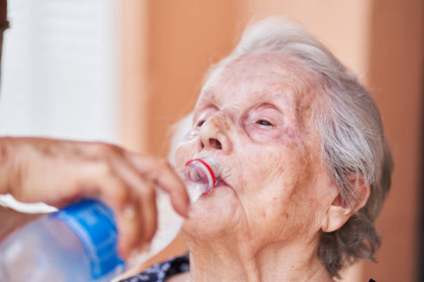 istock Woman helping elderly mother drink water 2203080020