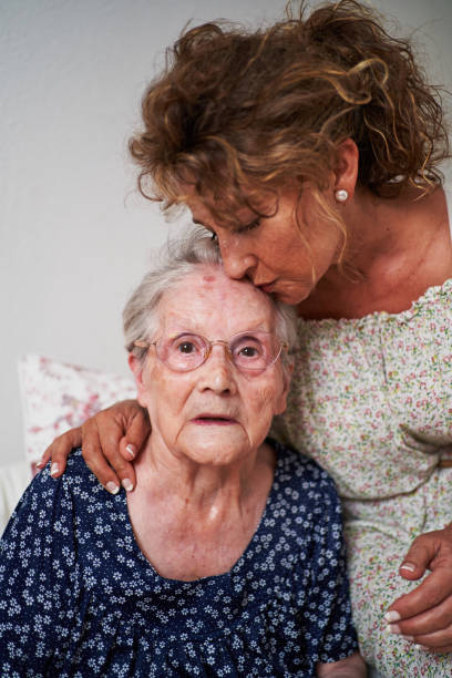 istock Mature daughter kissing elderly mother on forehead 2203080716