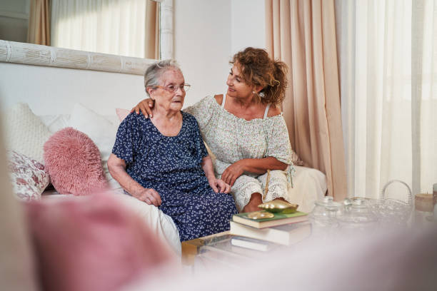 istock Daughter comforting elderly mother sitting on sofa at home 2203080878