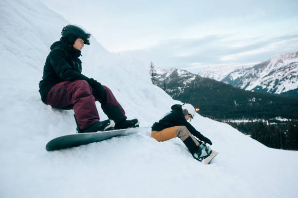 istock Snowboarding Teens Sit Down In Snow For a Rest 2203080947