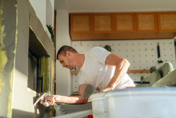 Plastering the fireplace Photo of a manual worker at construction site, plastering a fireplace drywall fireplace stock pictures, royalty-free photos & images