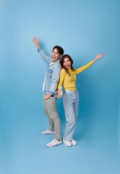 istock Surprised Asian couple standing smiling and opening hands welcome isolated on blue studio background. 2203081666