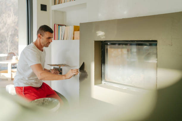 Plastering the fireplace Photo of a manual worker at construction site, plastering a fireplace drywall fireplace stock pictures, royalty-free photos & images