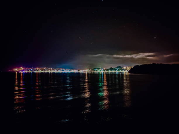 istock Night Sky With Stars Over City Lights Reflecting on Water Surface 2203083749