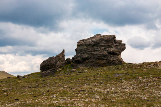 istock Rock Formations Against Cloudy Sky in a Vast Grassy Landscape 2203087617