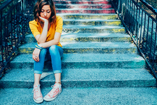 istock Depressed young woman sitting on staircase 2203089519