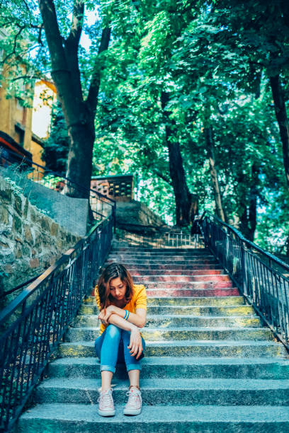istock Depressed young woman sitting on staircase 2203089686