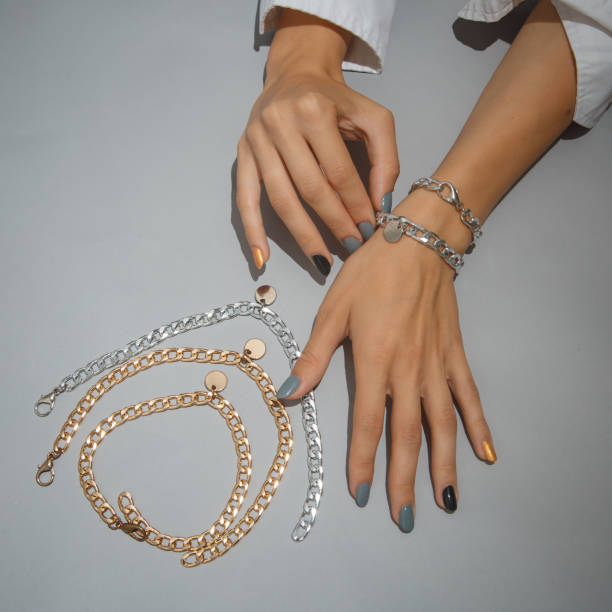 istock This image shows a person's hands adorned with various gold and silver chain bracelets and necklaces. 2203094233