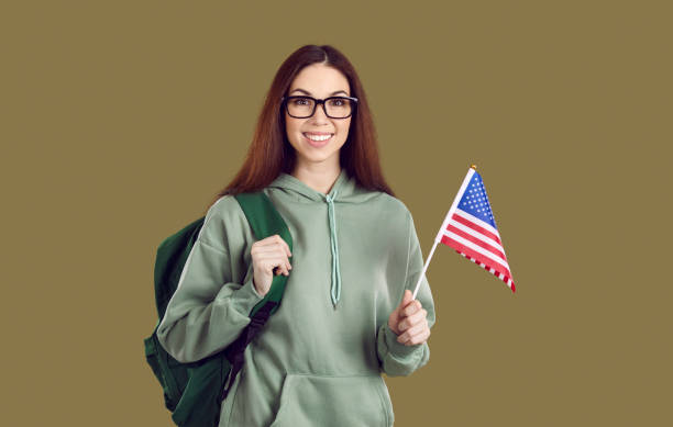 istock Smiling girl student with backpack hold american flag 2203096385