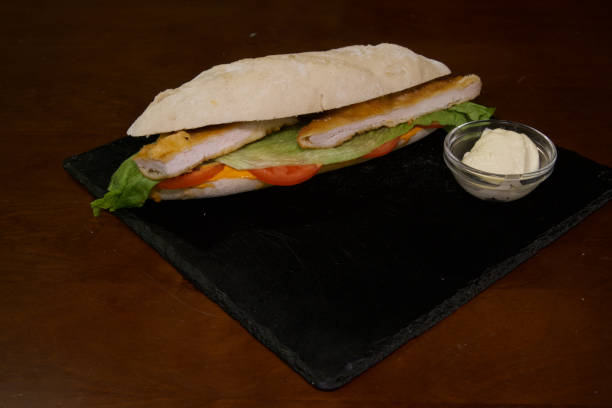 istock A sandwich with chicken and lettuce on a black plate 2203097021