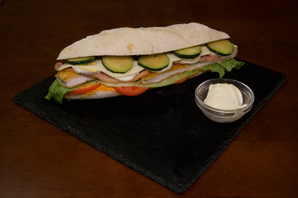 istock A sandwich with cucumbers and tomatoes on a black plate 2203097117