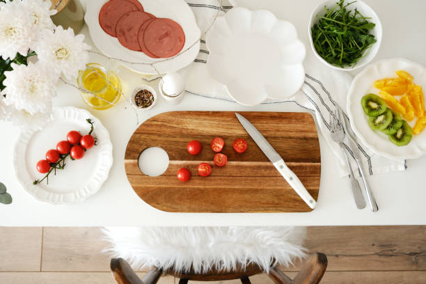 istock A beautifully arranged dining table with cutting board, fresh, vibrant ingredients - tomatoes, ham, aragula, fruits, olive oil, ready for cooking and meal preparation. 2203097627