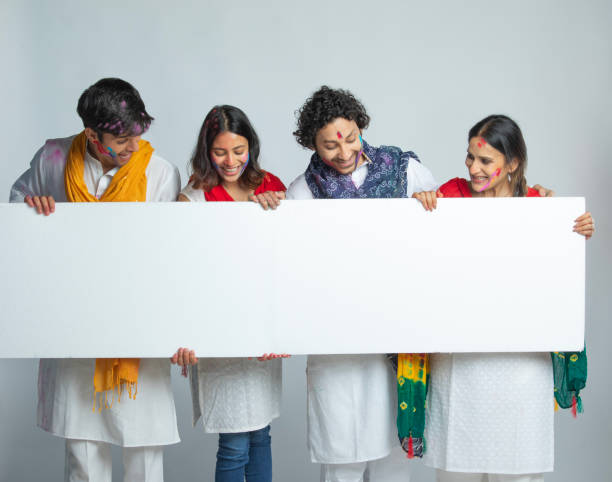 istock Happy friends with blank placard celebrating Holi on white background 2203104402