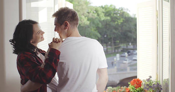 istock Couple in love enjoying the view from the window 2203104672