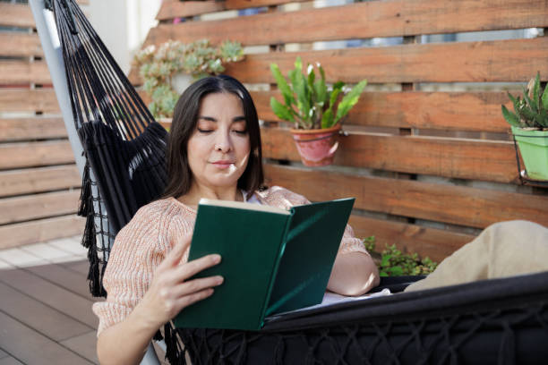 istock Woman relaxing in hammock reading a book 2203105647